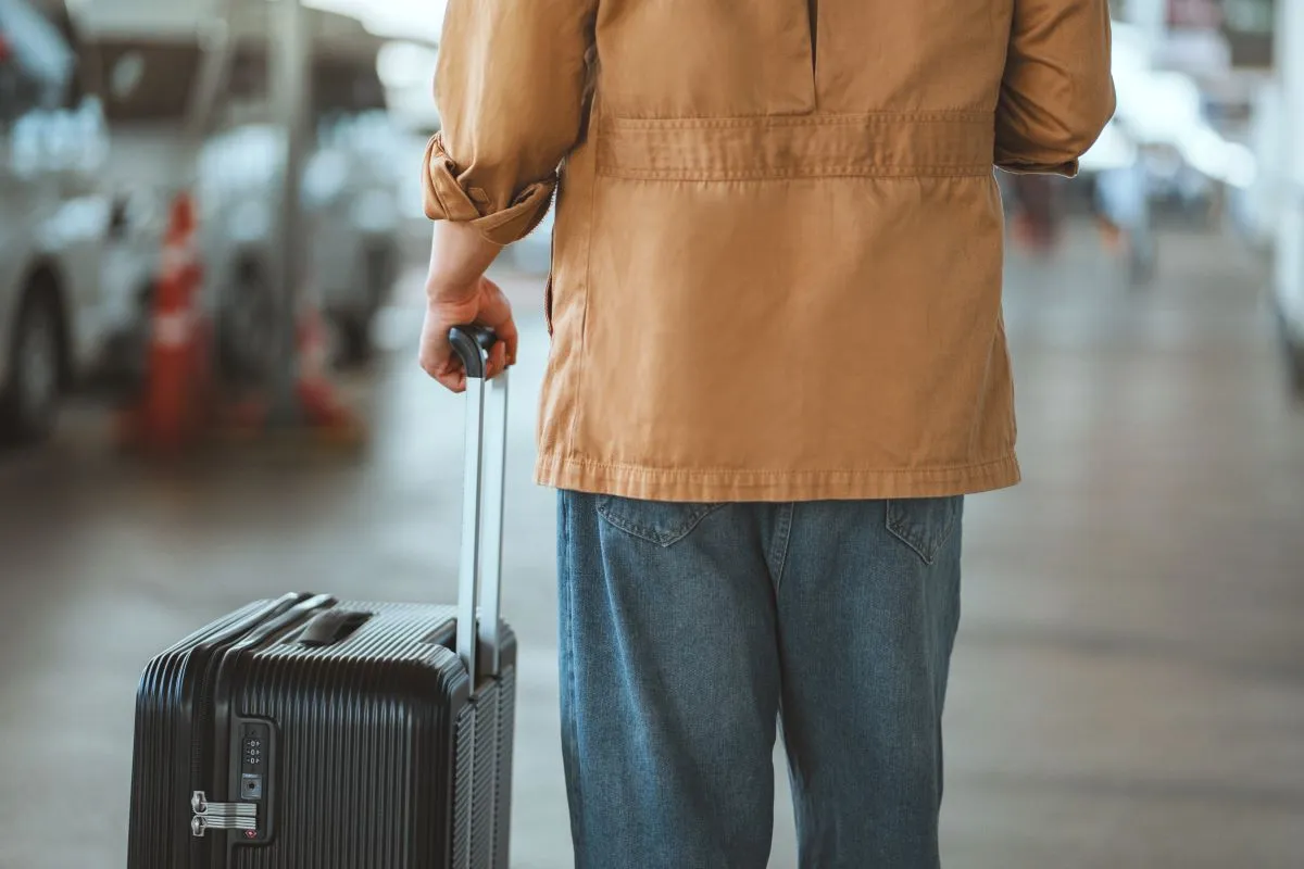 A traveller with a suitcase seen from behind
